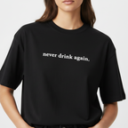 Person wearing a black t-shirt with 'never drink again.' text on a plain background